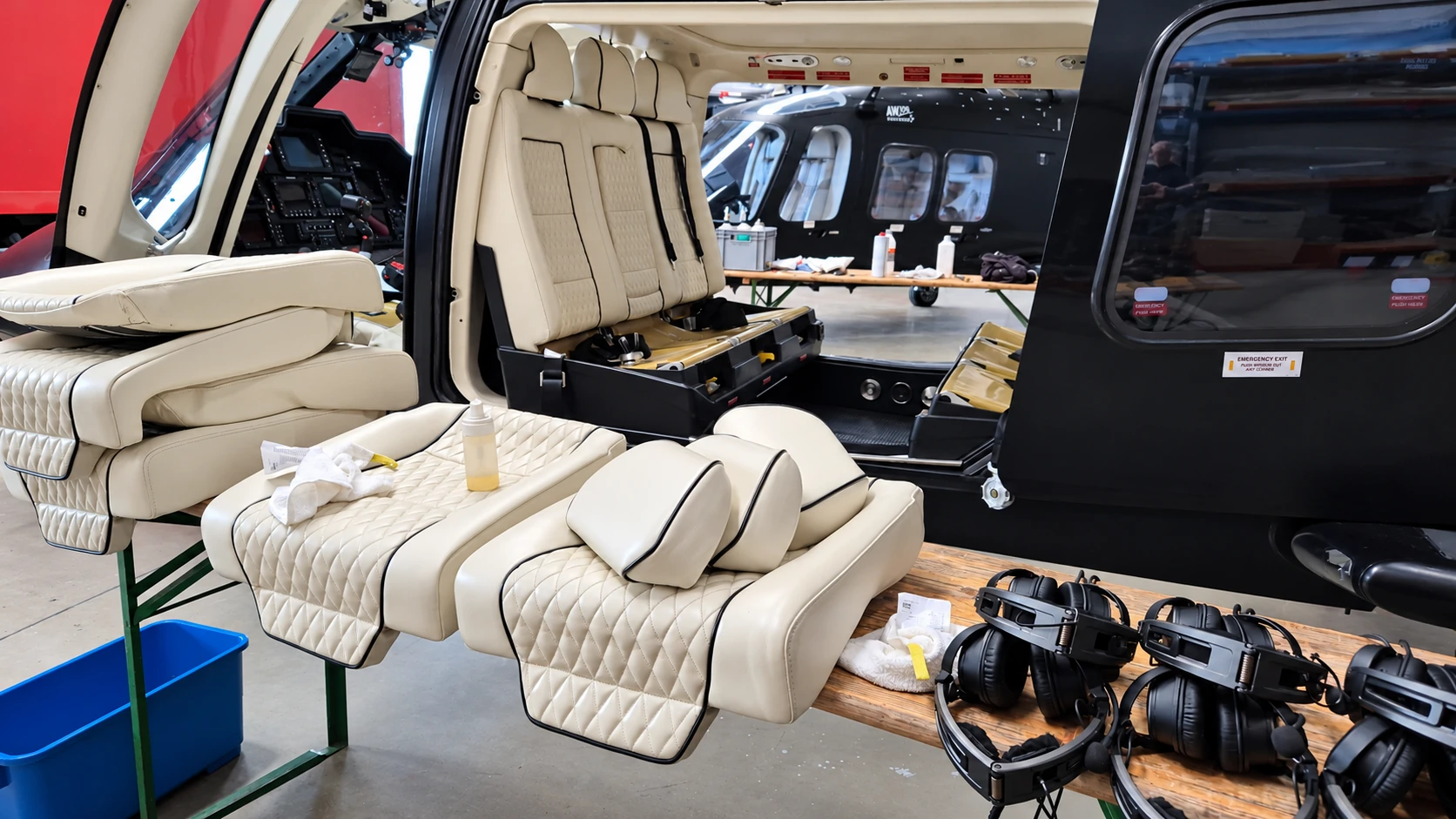 Ausgebaute cremefarbene Lederpolster neben einer geöffneten AW109-Kabine während der Reinigung
