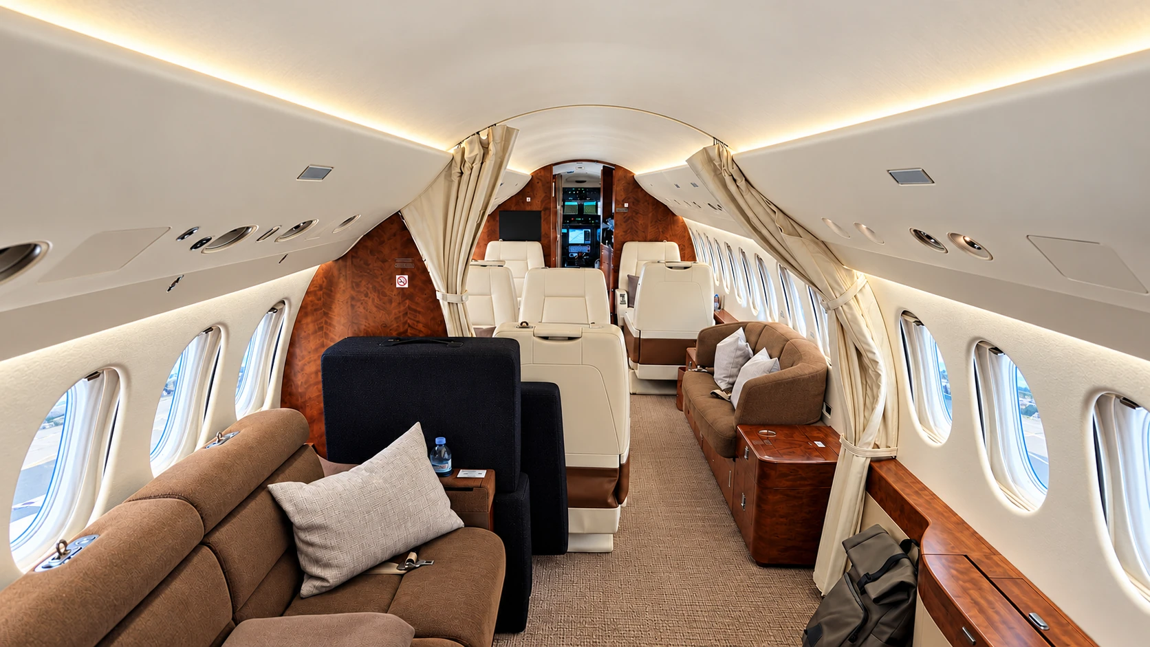 Blick durch eine Jet-Kabine mit hellen Ledersitzen, braunen Sofas und Holzverkleidungen