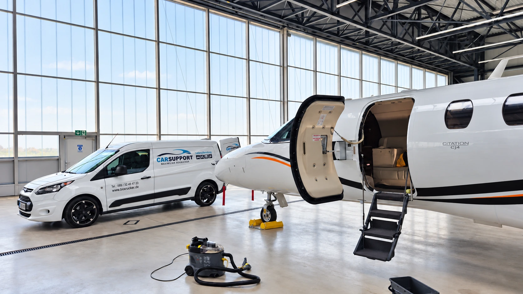CarSupport-Servicefahrzeug neben einem Flugzeug mit geöffneter Kabinentür im Hangar
