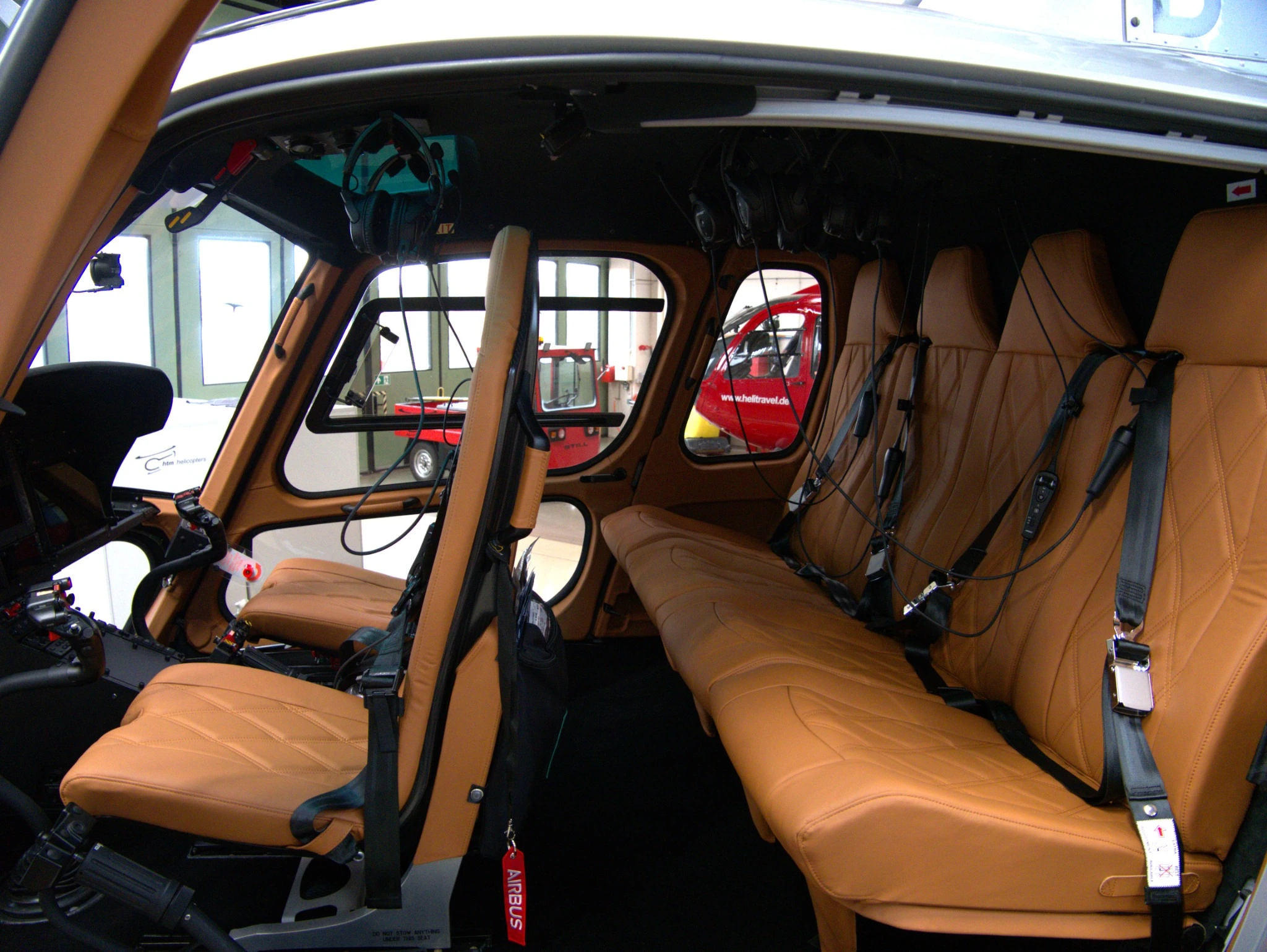 Helikopterkabine mit cognacfarbenen Ledersitzen, Sitzgurten und Headsets