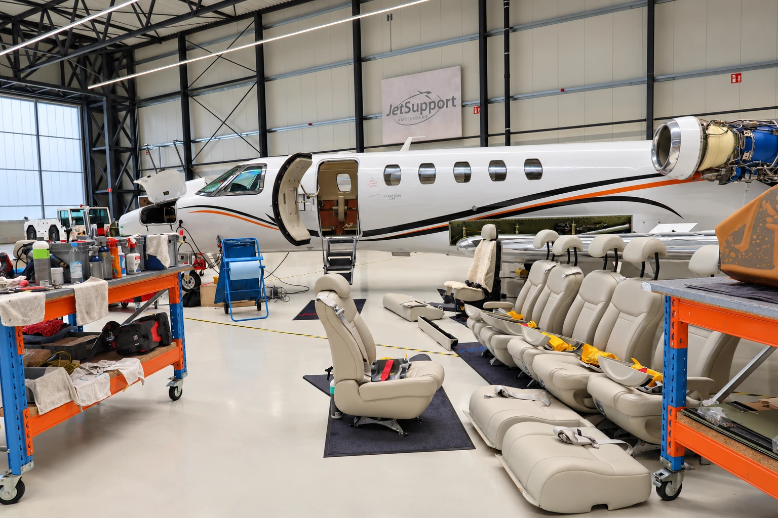 Ausgebaute Ledersitze und ein Pilotensitz mit Lammfellbezug vor einer Citation während einer großen Wartung