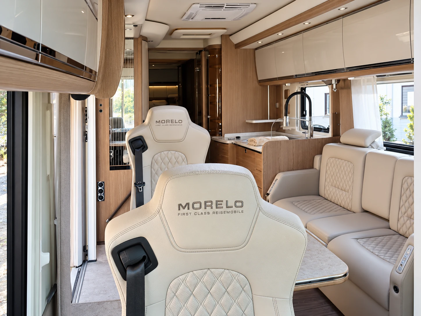 Gerade ausgerichtete Ledersitze und Sitzgruppe im Reisemobil mit hellen Lederbezügen und Rautensteppung
