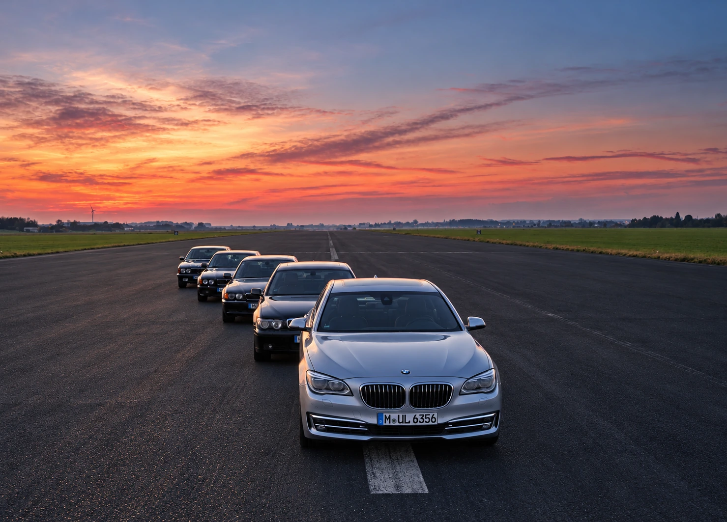 Fünf Automobile in einer Reihe auf einer Startbahn im Abendlicht