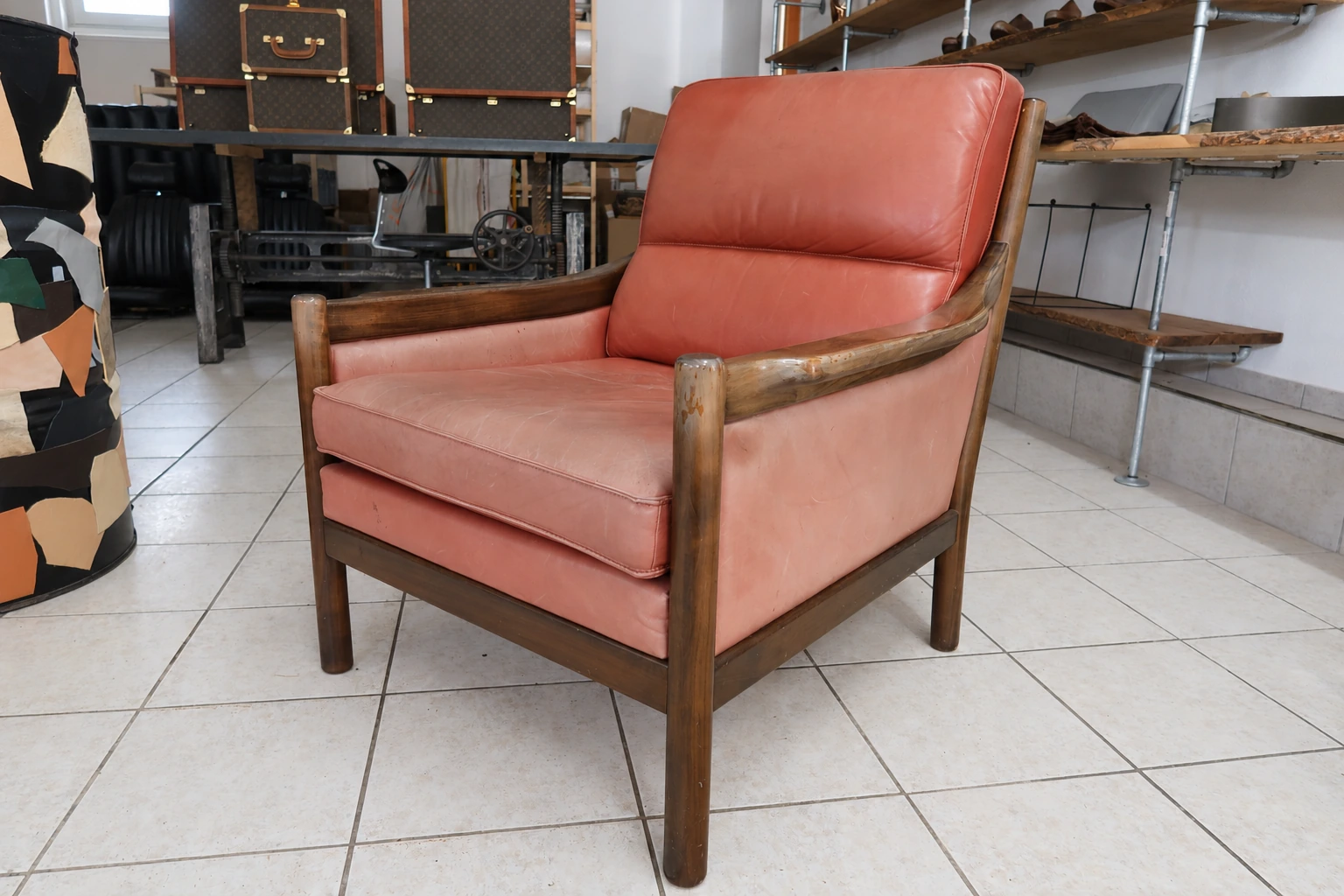 Coral-red leather armchair with a faded seat and signs of wear before treatment